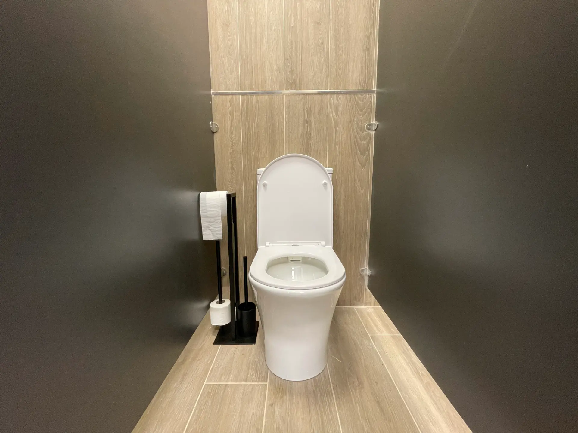 Inodoro blanco instalado en un baño con pared y suelo imitación madera